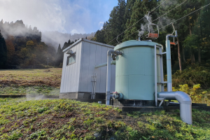 Ein großer grüner geothermischer Kraftwerkstank steht auf einem saftig grünen Feld umgeben von Bäumen und Pflanzen, mit Rauch, der aus dem Tank unter einem bewölkten Himmel aufsteigt.