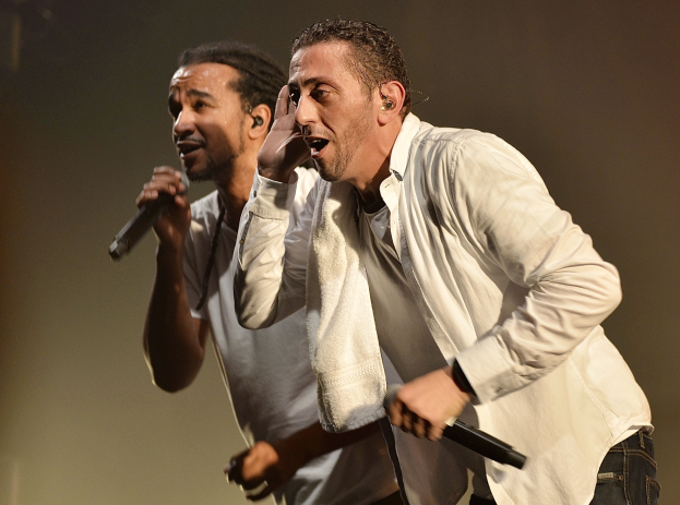 Zwei Männer in legerer Kleidung stehen nebeneinander auf der Bühne und halten jeweils ein Mikrofon in der Hand.