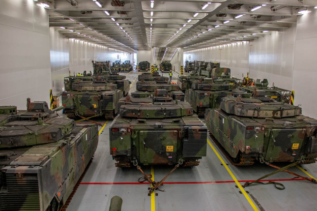 Ein grosser Militaraerraum mit Reihen von Militaraerfahrzeugen, beleuchtet von Deckenleuchten und von Waenden umgeben.