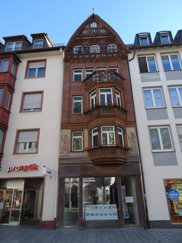 Ein Geschäftsgebäude mit vielen Fenstern an einer Straße unter einem klaren blauen Himmel, das in Heidelberg, Deutschland, zum Verkauf steht.