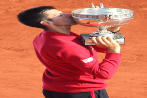 Novak Djokovic hält den French-Open-Pokal nach seinem Sieg gegen Rafael Nadal im Finale der Herren-Einzelkonkurrenz und feiert mit einem triumphierenden Gesichtsausdruck.