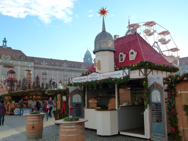 Ein pulsierender Weihnachtsmarkt in Nürnberg, Deutschland mit Menschen um geschmückte Stände, festliche Lichter, Schmuck, Gebäuden mit Fenstern, einem Riesenrad und einem bewölkten Himmel, mit einer Tafel mit Text auf der rechten Seite.