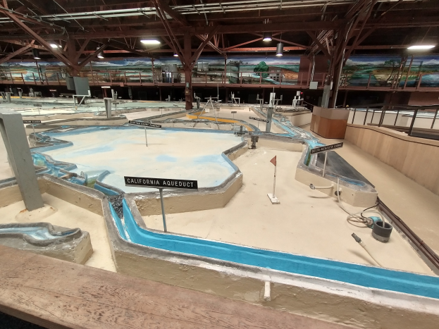 Großer Indoor-Wasserpark mit mehreren Wasserrutschen, Deckenbeleuchtung, Wandgemälden und einem Minigolfplatz.