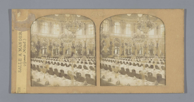 Ein Schwarz-Weiß-Foto eines prächtigen Hotelballsaals mit Tischen, Stühlen, üppigen Kronleuchtern und hohen Fenstern, auf dem links ein Schild mit der Aufschrift "Sale a Manger, Grand Hotel" zu sehen ist.
