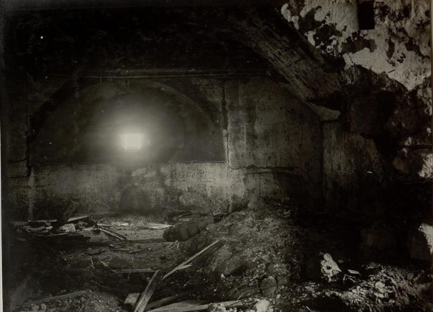 Ein Schwarz-Weiß-Foto eines zerfallenden Tunnels in den Berliner Mauerruinen, mit Schutt auf dem Boden und einem Licht am Ende