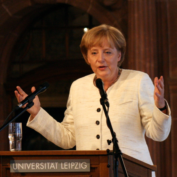 Bundeskanzlerin Angela Merkel bei einer Rede an der Universität Leipzig, hinter einem Rednerpult mit einem Mikrofon und einem Glas Wasser.