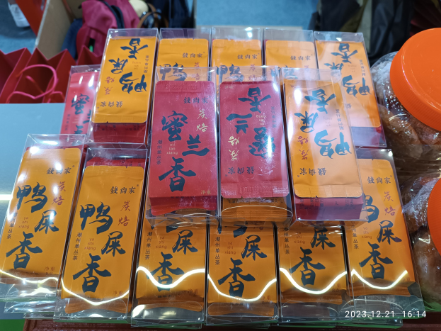 Ein Tisch mit verschiedenen verpackten Lebensmitteln und Gegenständen während einer Feier zum chinesischen Neujahr, mit einer Person im Hintergrund.