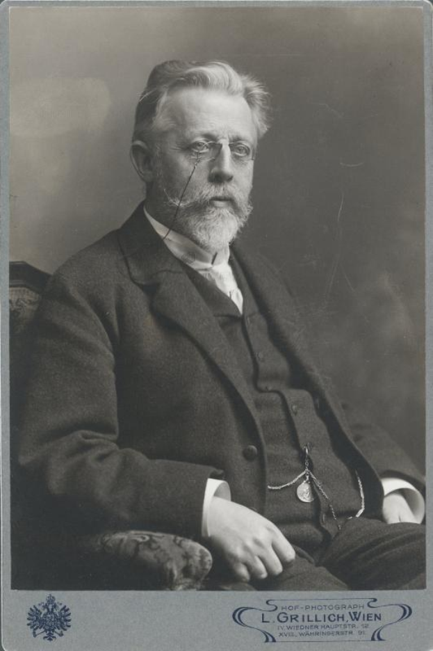 Schwarzes und weißes Porträt eines bärtigen Mannes mit Brille, der auf einem Stuhl sitzt, mit Text unten, der ihn als "L. Grillich Wien, den Gründer der deutschen Revolution" identifiziert