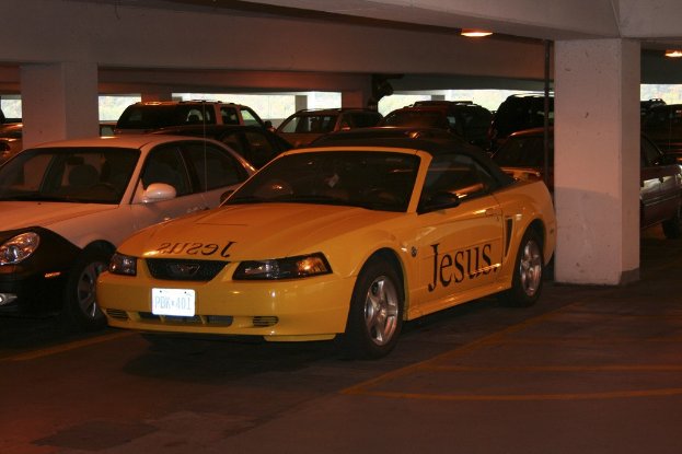 Ein überfüllter Parkplatz mit zahlreichen geparkten Autos vor einem Gebäude.