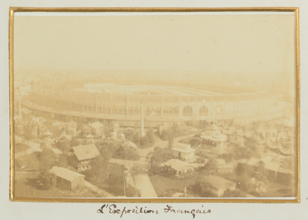 Altes Schwarz-Weiß-Foto eines Stadions inmitten einer städtischen Umgebung, umgeben von Gebäuden, Bäumen und Strommasten, mit Text am unteren Rand.