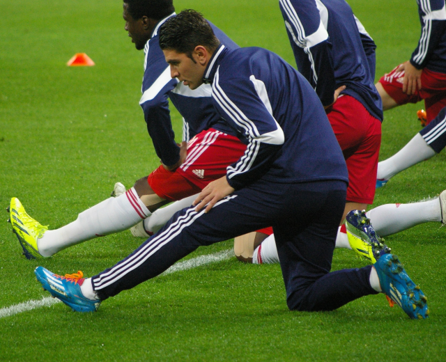 Gruppe von Männern in Sportkleidung, die auf einem Rasenfußball spielen.